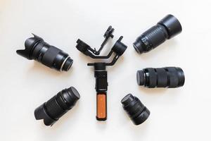 Top view of work space videographer with digital gear, gimbal stabilizer, lens and camera accessory on white table background photo