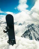 Black one snowboard in snow with white mountains in the background. Concept of end of ski season.Gudauri. Sakartvelo. Georgia winter holidays panorama photo