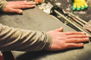 Man hands lay on snowboard base before wax in repair shop. Service and snowboard preparation concept photo