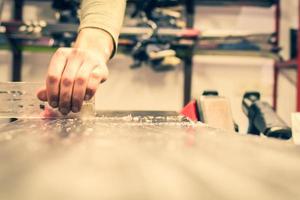 Repairman scrape wax off from snowboard with scraper in repair shop ski rental. Step by step guide photo