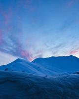 Panoramic view of beautiful winter wonderland mountain scenery with purple pink sunset background in the Alps. Majestic evening light at sunset photo