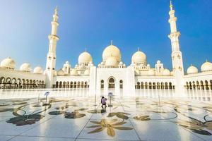 abu dhabi, emiratos árabes unidos, 2022 - turista en la mezquita sheikh zayed en un día de cielo azul claro, abu dhabi, emiratos árabes unidos foto