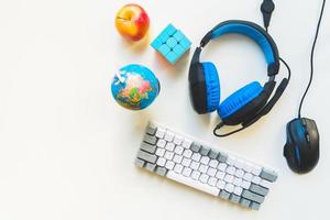 Above top view student workspace concept, mouse, keyboard, headset on white background with copy space and kids development. Elementary remote study set up. Study from home concept photo