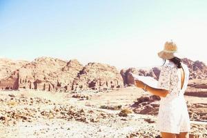 turista caucásica de moda, lee el mapa, planea explorar los lugares de interés de la antigua y fabulosa ciudad de petra en jordania. fotos coloridas. concepto de ocio, vacaciones y viajes.