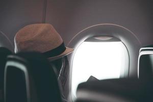 Woman looks out the window of an flying airplane wings view. Young passengers are traveling by plane, watching the sky from above photo