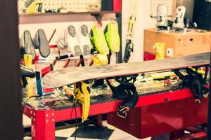 Close up waxed snowboard on repair workshop table. Messy workshop and work space in ski shop. Step by step guide photo