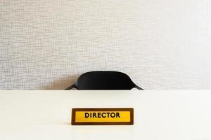 Wooden director office plate on white glossy table with empty chair in room photo