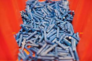 Plastic blue dowels on red background, wall plugs for fixation and installation, close up, top view photo