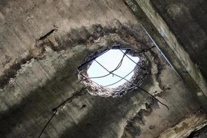 Abandoned damaged roof with hole in ceiling overlooking cloudy sky, close up photo