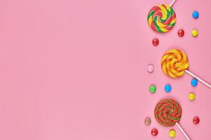 piruletas dulces y caramelos sobre fondo rosa foto