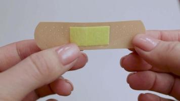 A man opens a band-aid. First aid for trauma. The medicine. Isolated background. Video. video