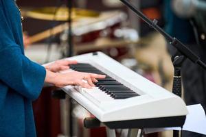 Musician woman playing on synthesizer keyboard piano, hands press synthesizer keys on concert stage photo