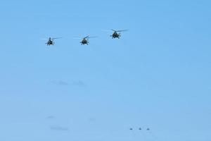 Military helicopters flying in blue sky performing demonstration flight, aerobatic team, air show photo