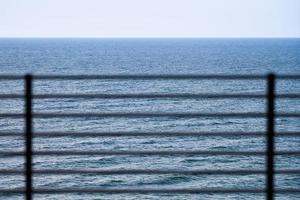 Fencing on observation deck, blue sea background, protection of tourists from falling off cliff photo