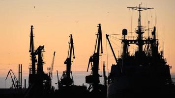 Silhouettes of ships and container cranes in sea port photo
