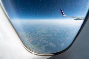 vista de la ventana del avión al cielo nublado y la tierra. hermoso paisaje desde la cabina del avión. volar sin miedo a volar, incidentes y turbulencias. foto