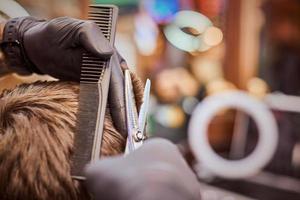 corte de pelo masculino en la barbería de cerca, cliente que se corta el pelo por peluquero con peine y tijeras