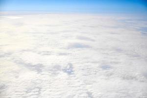 Breathtaking over clouds view from aircraft window, thick white blue clouds looks like soft foam photo