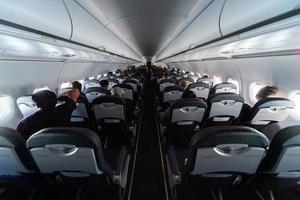 Airplane cabin seats with passengers. Economy class of new cheapest low-cost airlines without delay or cancellation of flight. Travel trip to another country. photo