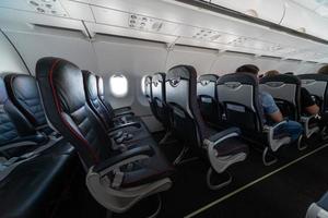 Airplane cabin seats with passengers. Economy class of new cheapest low-cost airlines without delay or cancellation of flight. Travel trip to another country. photo