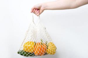 Closeup of a woman's hand holding eco-friendly shopper with fresh vegetables. Sustainable shopping concept.Healthy eating photo