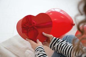 Close up of woman hold gift box red heart for Valentines Day.Delivery present. photo