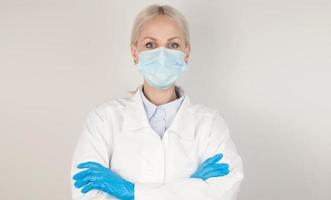 Covid19, coronavirus, healthcare.Closeup Portrait of young doctor in medical coat wearing mask amd gloves against gray background photo