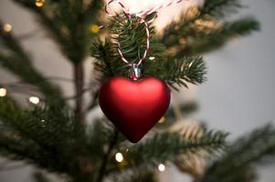 Christmas or new year banner with heart shaped ornament haning on branches with bokeh from lights. photo