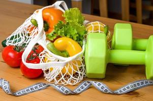 Healthy diet concept. Vegetables in string bag near mesuring tape. Vegetarian,vegan.Sport lifestyle. Dumbbells photo
