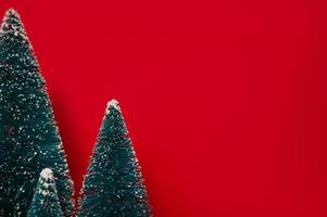 Isolated group of full artificial firs like a small forest tree against red background.Mockup,Christmas or new year. Minimalistic banner photo