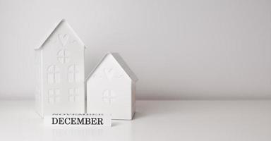 pancarta blanca de invierno con casas de juguete y letrero de diciembre. comienzo del invierno. vacaciones de temporada. lugar para texto foto