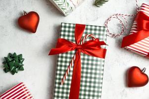 Christmas flat lay in classical red and green colors. Gift boxes,ornaments,fur branches and wrapping paper on white concrete background photo