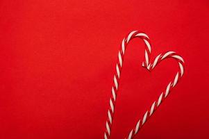 Two candy canes making a heart on a red textured background. Minimalistic christmas banner.Copyspace photo