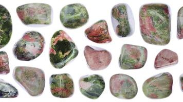 Unakite jewel stones set texture on white light isolated background. Moving right seamless loop backdrop. video