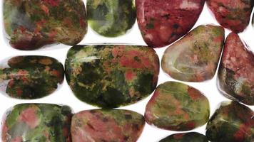 Unakite heap jewel stones texture on white light background. Moving right seamless loop backdrop. video