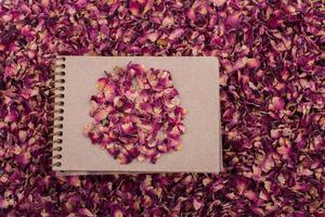 pétalos de rosa secos en un cuaderno de espiral foto