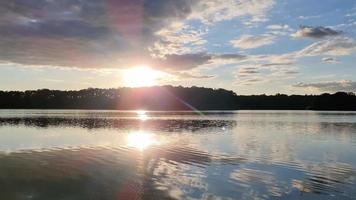 mooi zonsondergang landschap Bij een meer met een reflecterende water oppervlak. video