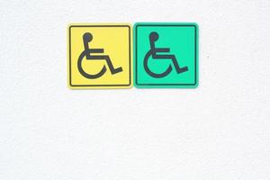 Yellow and green disabled signs on white wall background. Handicapped accessible sign of wheelchair. Concept of comfortable pathway for people barrier-free urban environment in city. photo