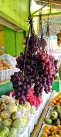 varios racimos de uvas colgando en la frutería, foto tomada desde el ángulo lateral