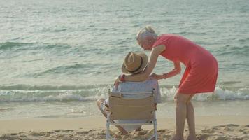 An elderly couple hugs their shoulders at the beach on their summer vacation and they smile and enjoy their vacation. photo