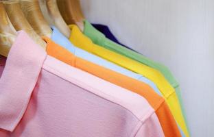 Many colorful shirts hanging on a rack photo