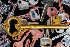 Golden master key in the center of the image. with pattern many keys on black floor photo