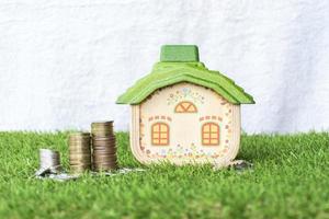 Mock up house with coins stack on grass floor and white background photo