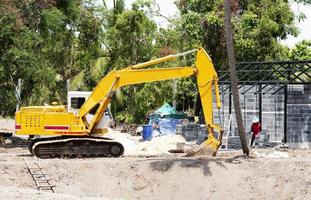 Yellow excavator digging in construction site photo