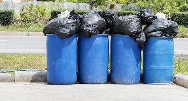 cuatro viejos cubos de basura azules con bolsas de basura en la acera foto