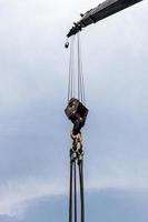 Crane boom with hooks and blue sky background photo