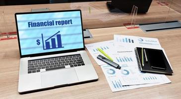 Financial report presentation on display laptop and paperwork on table in meeting room photo