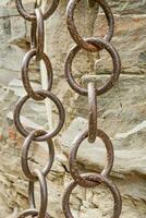 Matal chains pairs hanging by the side of a rock side