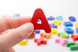 Letter A in hand beside colorful letter blocks photo