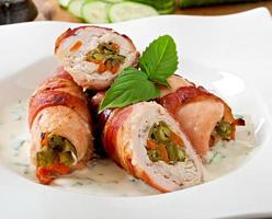 Delicious chicken rolls stuffed with green beans and carrots wrapped in strips of bacon photo
